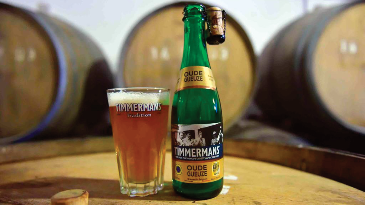 Oude Gueuze Timmermans in primo piano. Botti in legno sullo sfondo